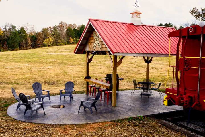 Outdoor space with a grill and dining set underneath a covered pavilion and chairs around an outdoor fire pit.