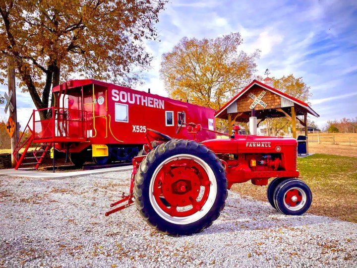 Red Southern caboose and pavilion in the background, with a red tractor in the foreground.